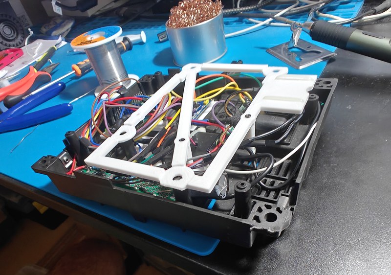 Wired electronics under a white printed frame in the black housing.